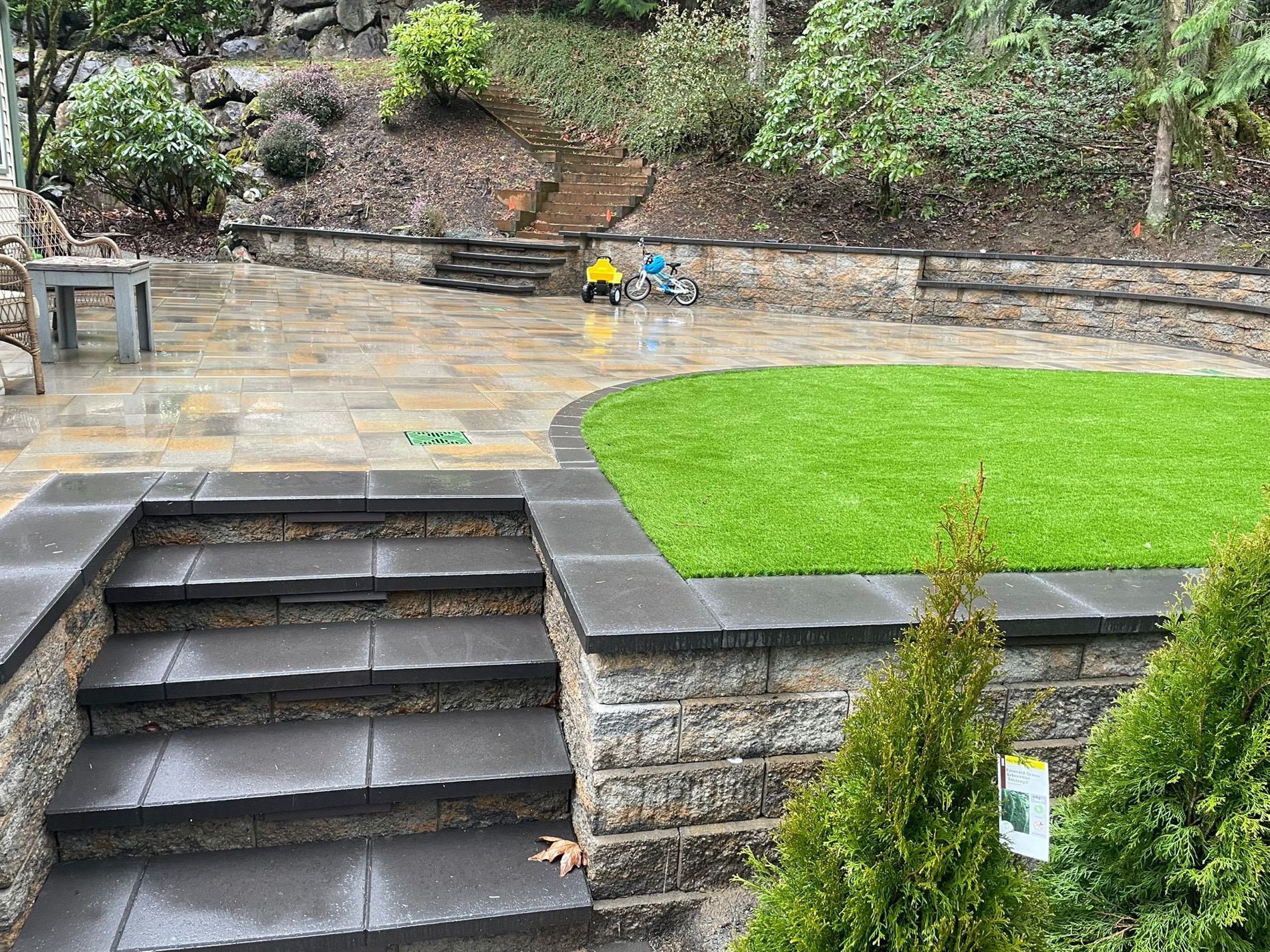 Finished paver patio with green lawn and stone retaining wall