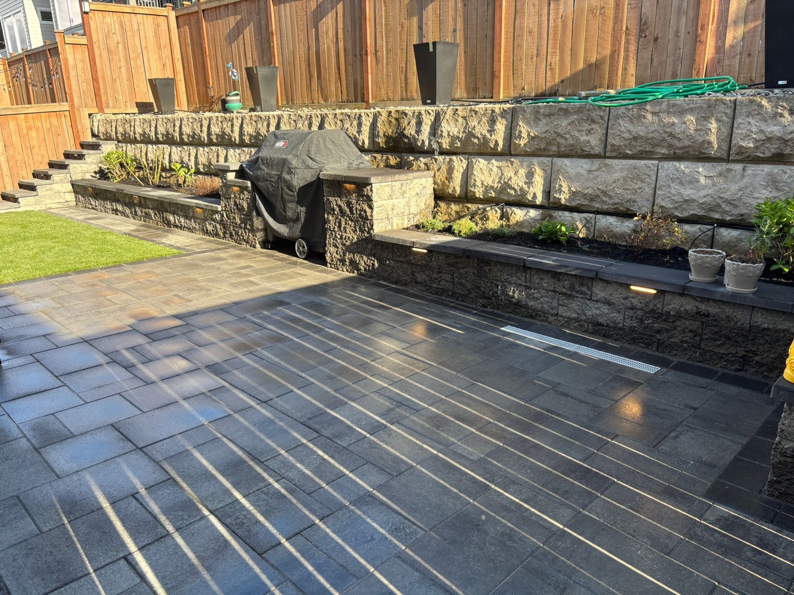 Backyard retaining wall, paver patio, lighting, and lawn