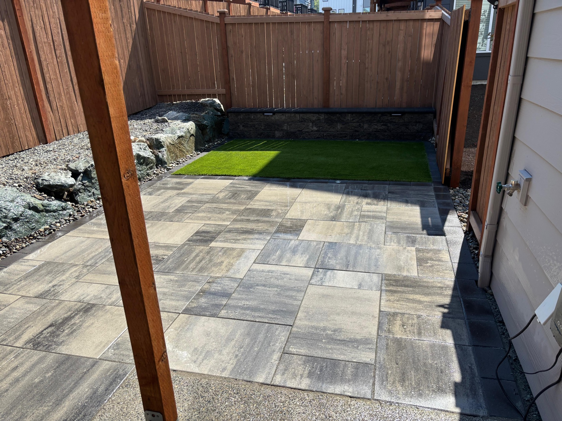 Finished backyard patio with turf, retaining wall, and pavers