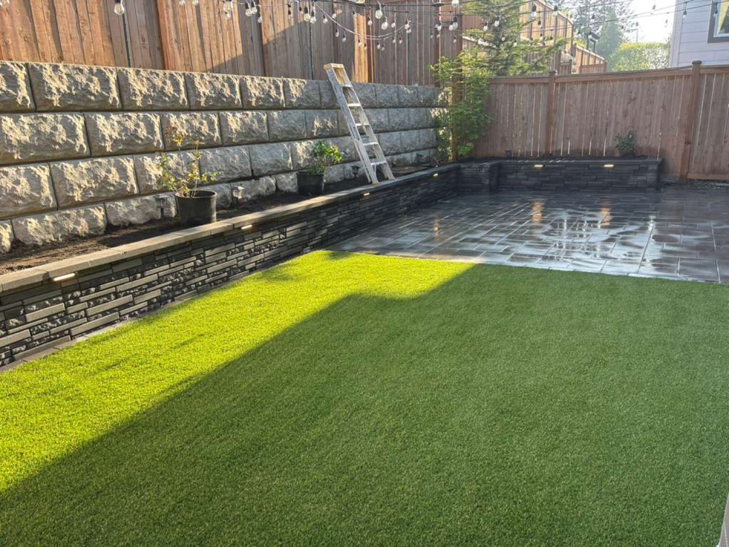 Backyard turf and retaining wall with paver patio