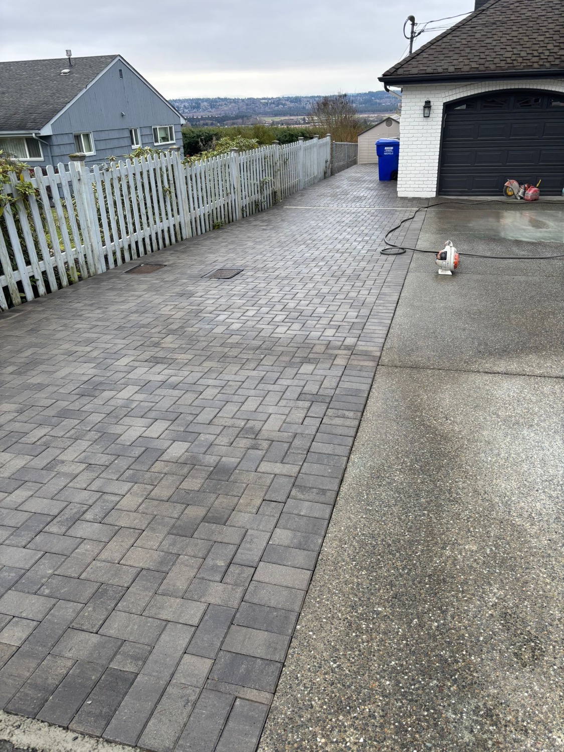 Driveway and entry paver installation near white fence