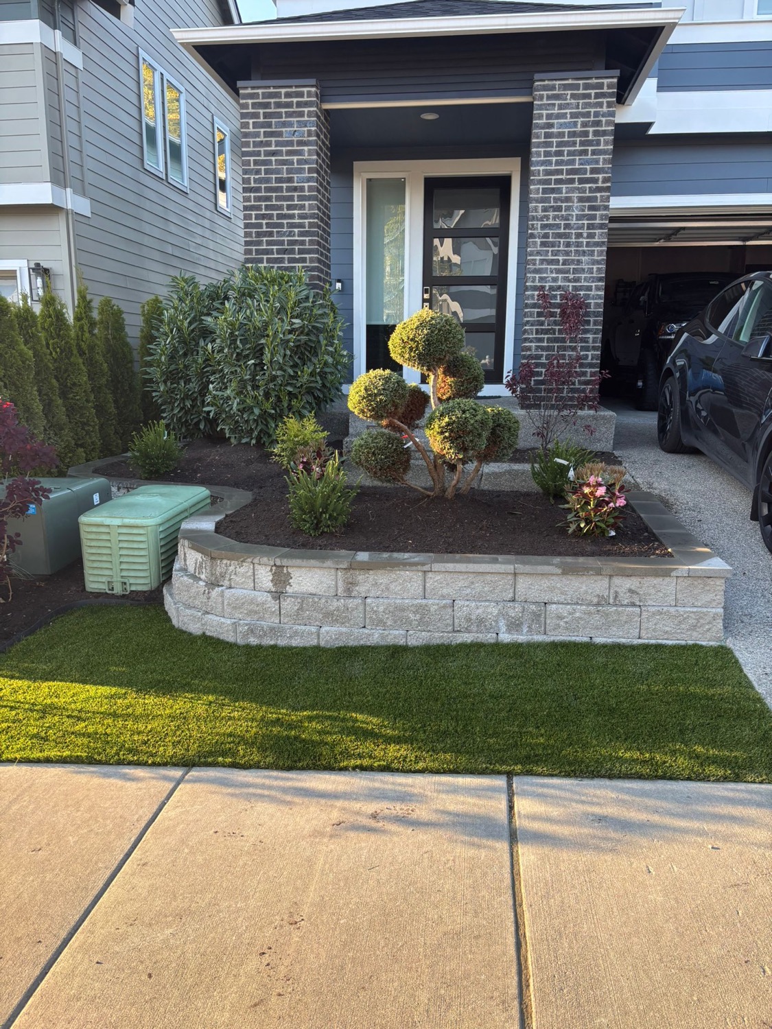 Front entry planting bed with shrubs, mulch, and stone wall