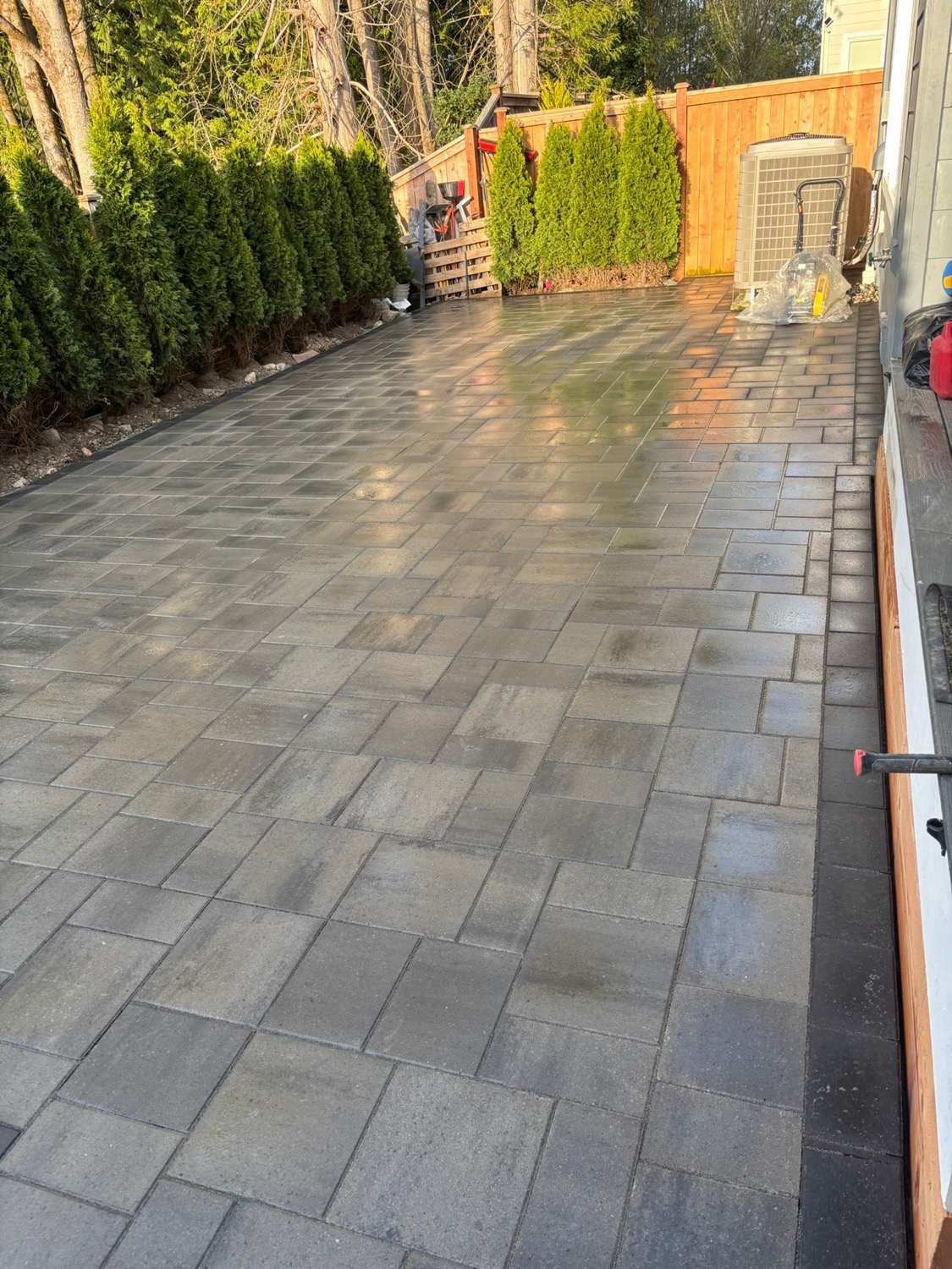 Finished paver patio with privacy hedges and wood fence