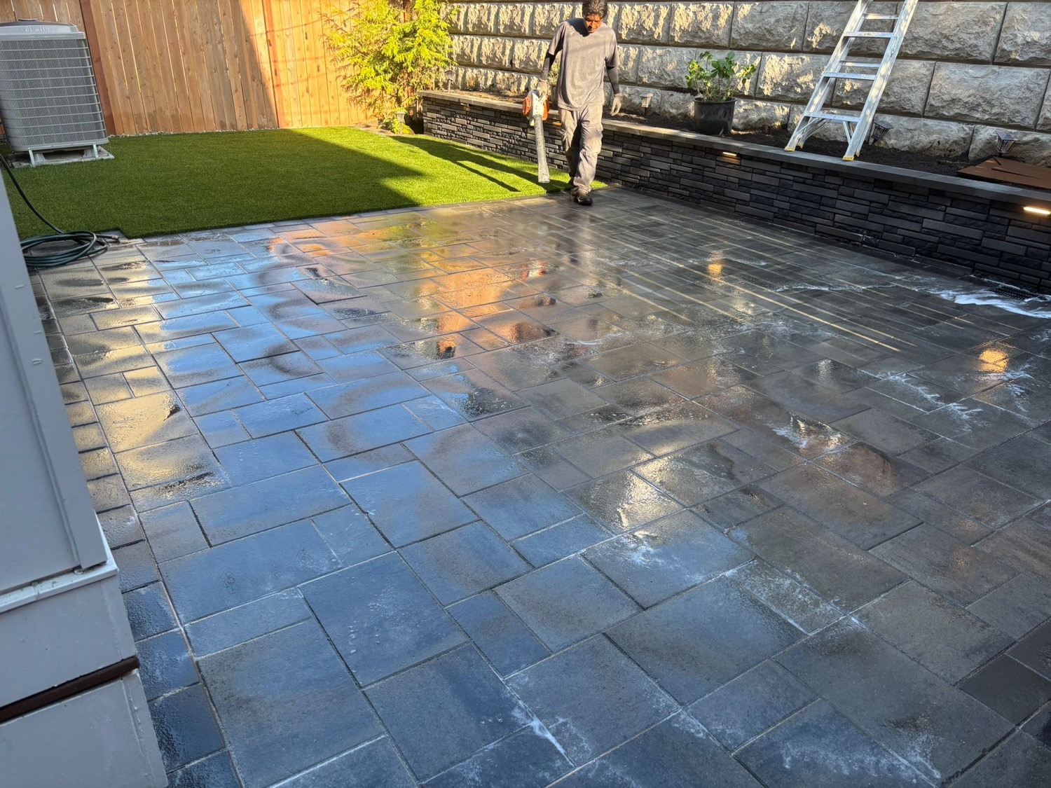 Artificial turf beside paver patio and retaining wall